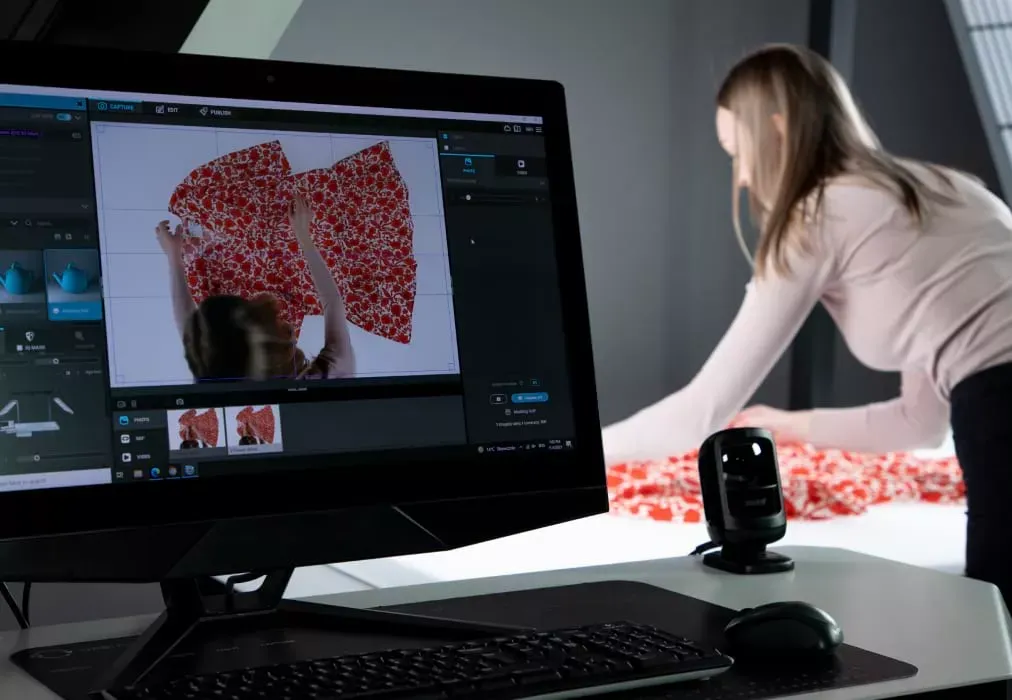 Fotograf justerer stoffplagg med blomst-mønster med live-visning på skjerm