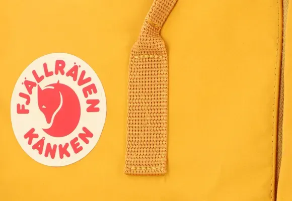 Nærbilde av gul Kanken-ryggsekk-logo og reim