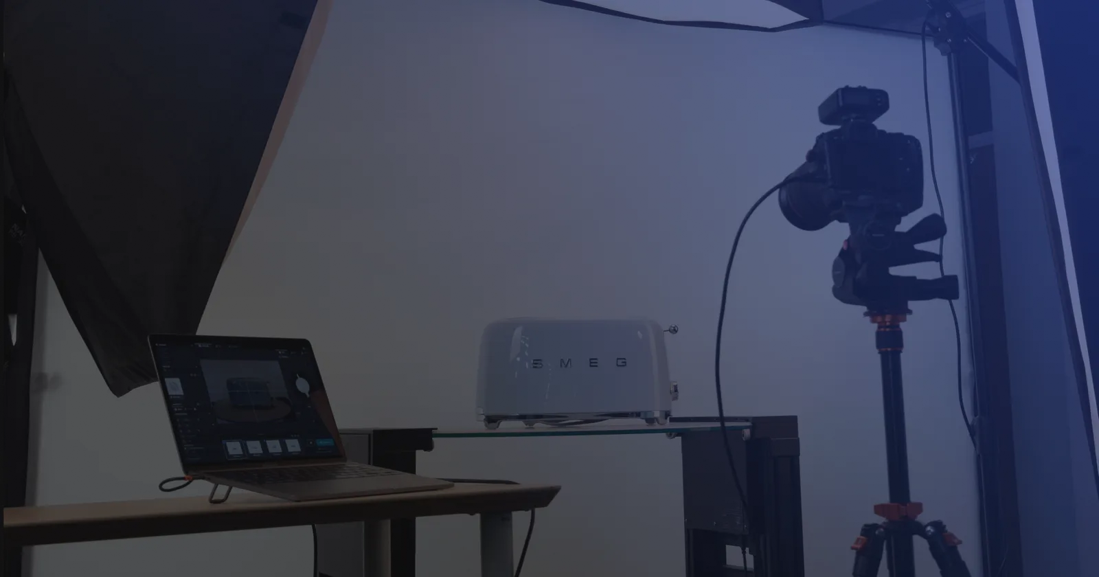 Produktfotostudio med tethering - en laptop med opptaksprogramvare ved siden av et kamera på stativ og et produkt på en glasshylle
