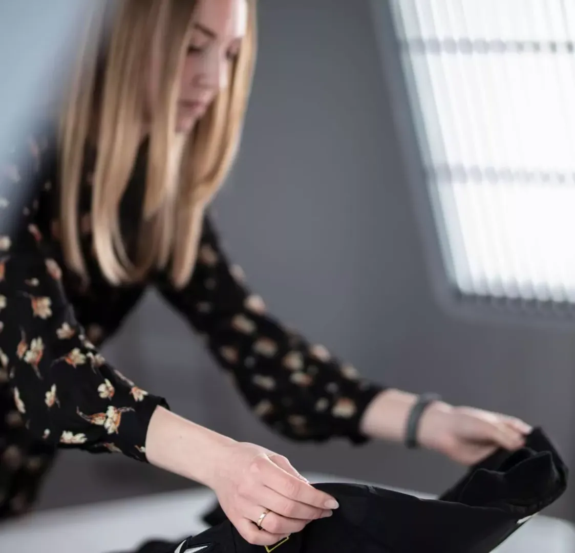 Produktstylist som klargjør svart plagg for flat lay-fotografering