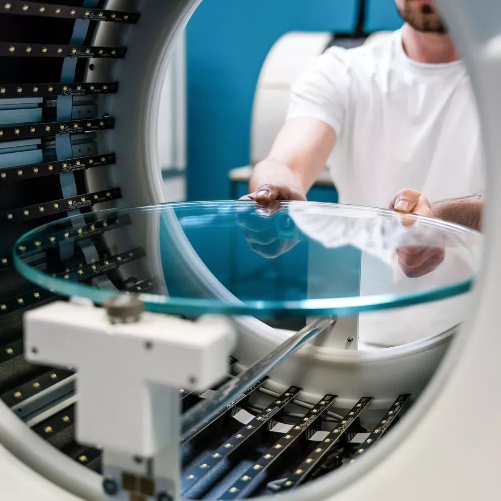Tekniker som plasserer glassdreieskive i automatisert fotostudio