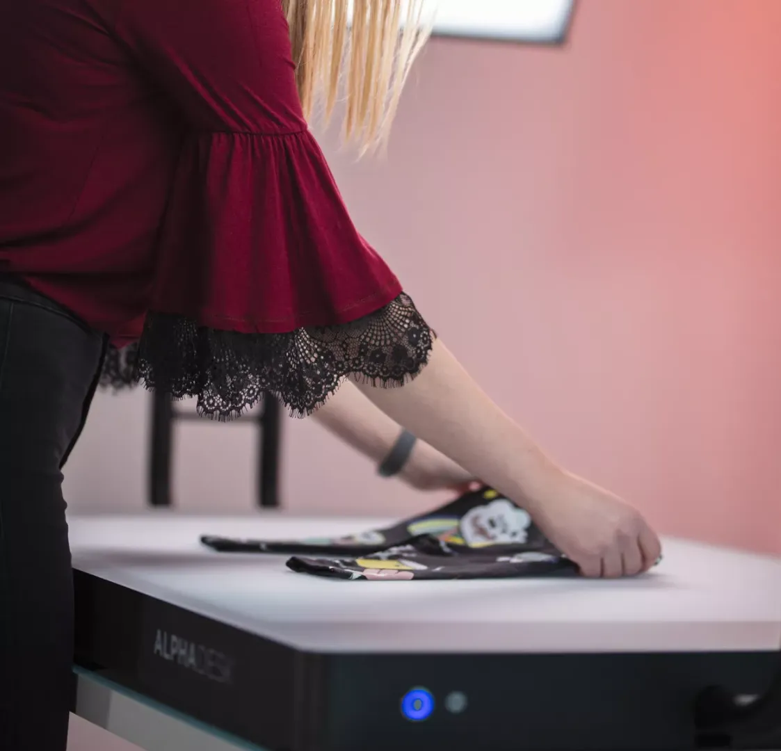 Kvinne som bretter barneklær på et hvitt skrivebord med Alphadesk